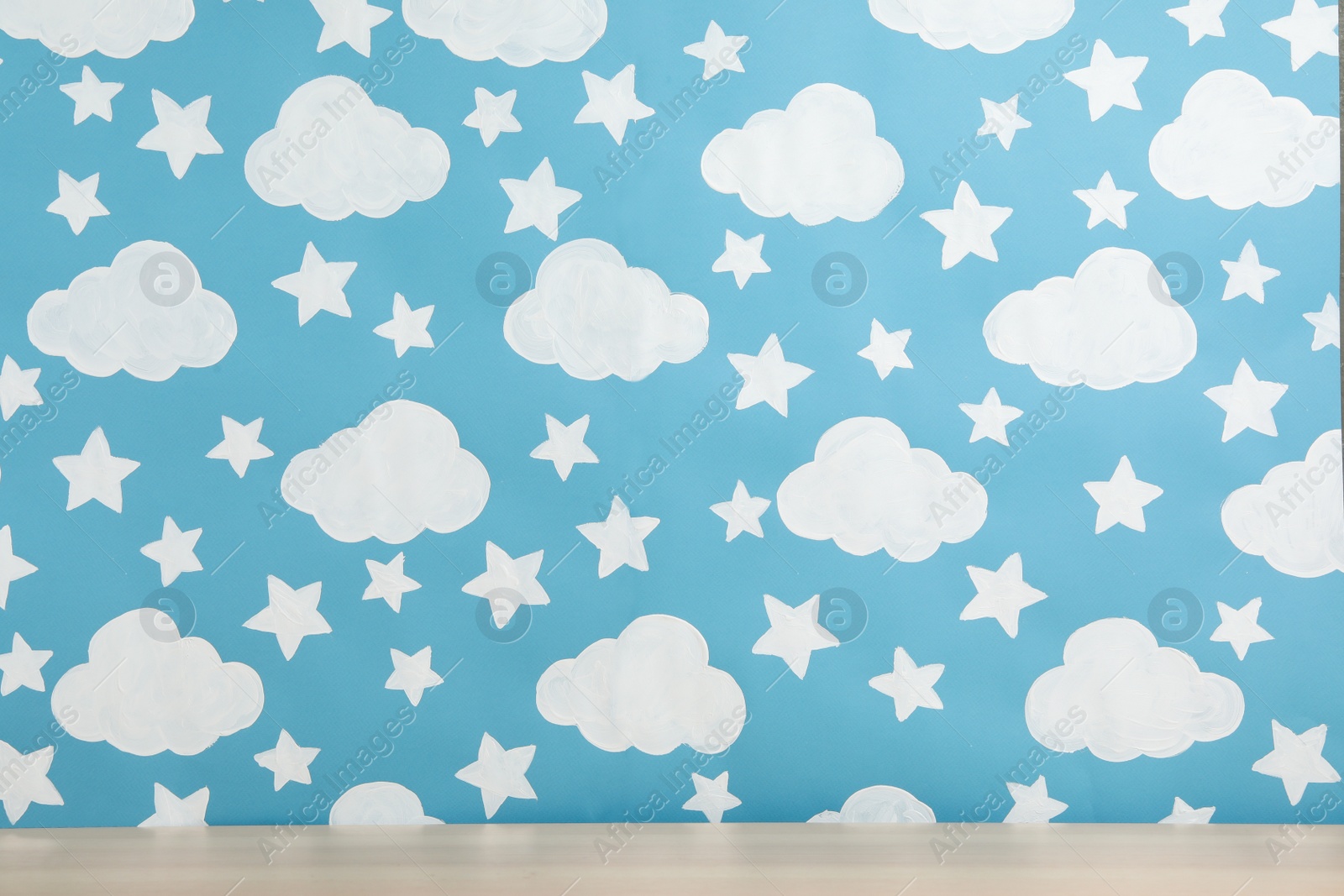 Photo of Wooden table near wall with painted blue sky. Idea for baby room interior