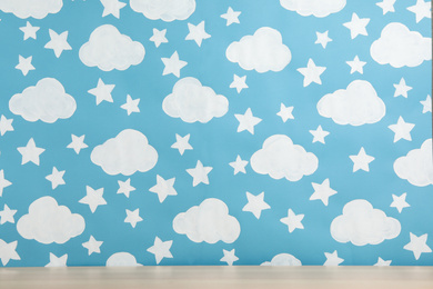 Wooden table near wall with painted blue sky. Idea for baby room interior