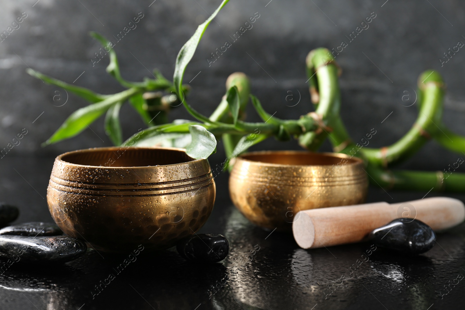 Photo of Retreat concept. Singing bowls, spa stones and bamboo stems on wet mirror surface, closeup. Space for text