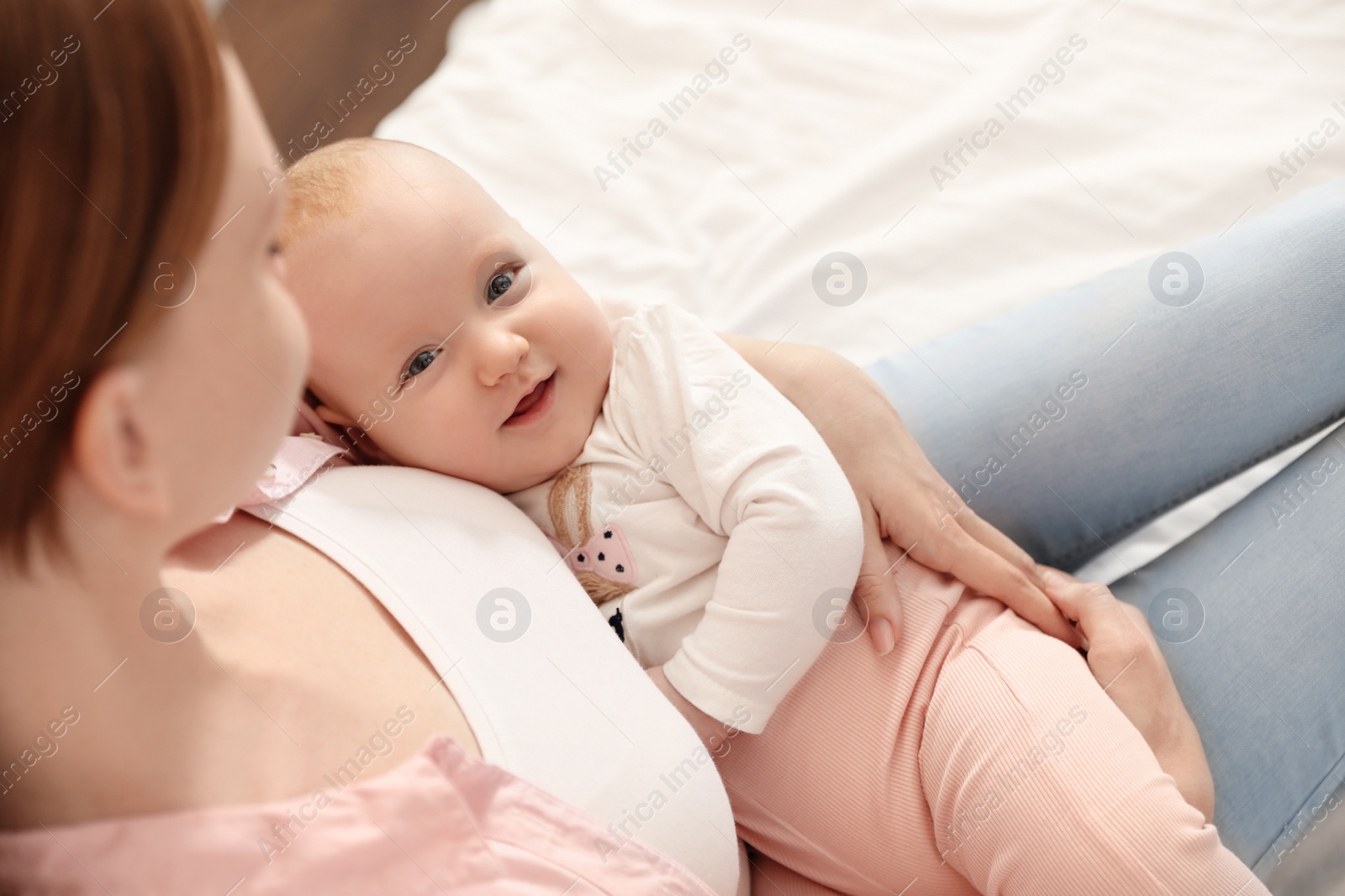 Photo of Young woman with her little baby resting after breast feeding on bed, above view