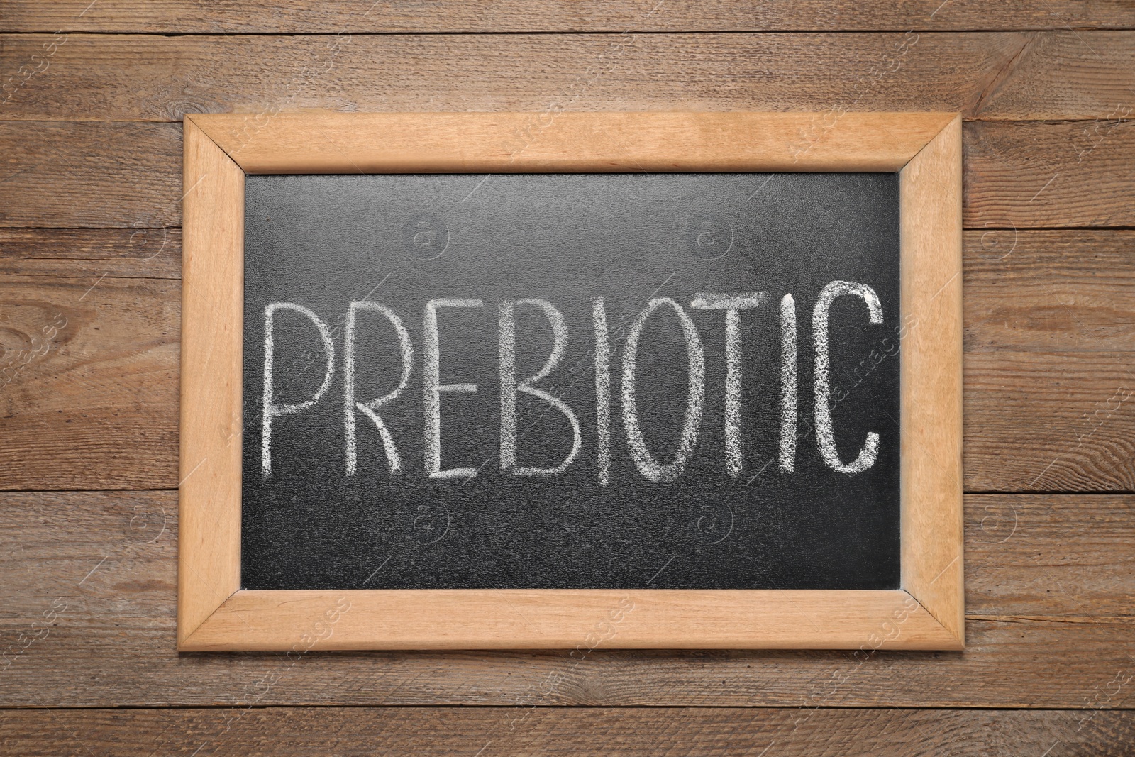 Photo of Blackboard with word Prebiotic on wooden table, top view