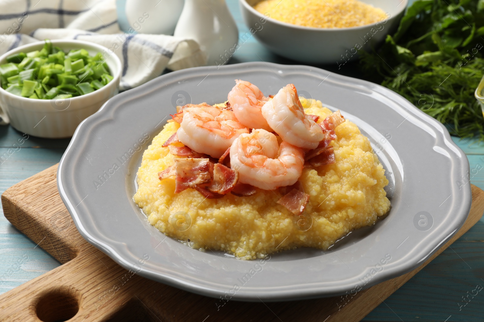 Photo of Plate with fresh tasty shrimps, bacon and grits on light blue wooden table