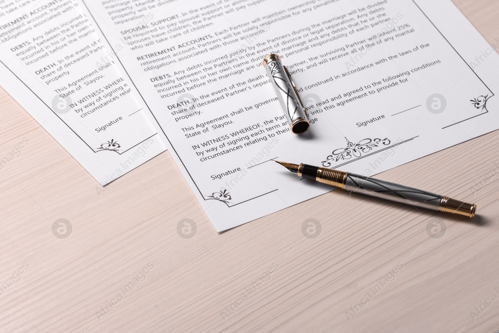 Photo of Marriage contracts and pen on light wooden table, space for text