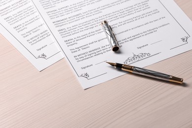 Marriage contracts and pen on light wooden table, space for text