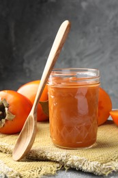 Photo of Delicious persimmon jam in glass jar served on table