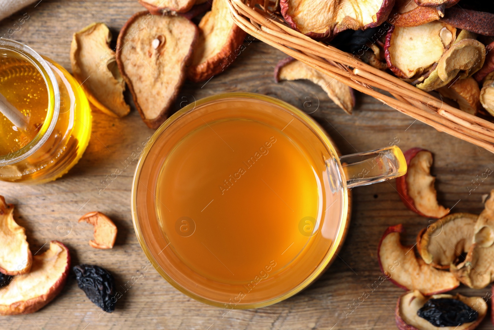 Photo of Delicious compote in glass cup, honey and dried fruits on wooden table, flat lay