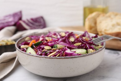 Eating tasty salad with red cabbage and pumpkin seeds on marble table, closeup