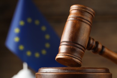 Closeup view of wooden judge's gavel and European Union flag on blurred background, closeup. Space for text