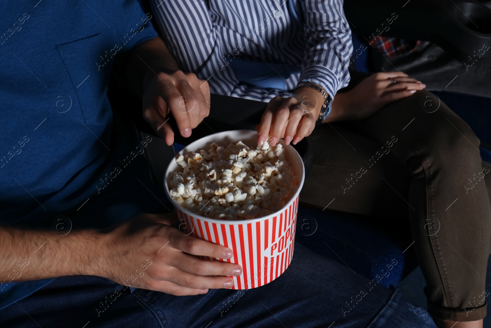 Photo of Young couple with popcorn watching movie in cinema, closeup