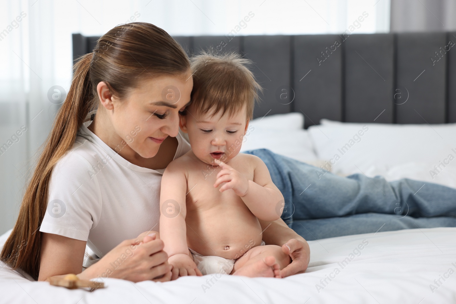 Photo of Mother with her baby on bed at home. Space for text