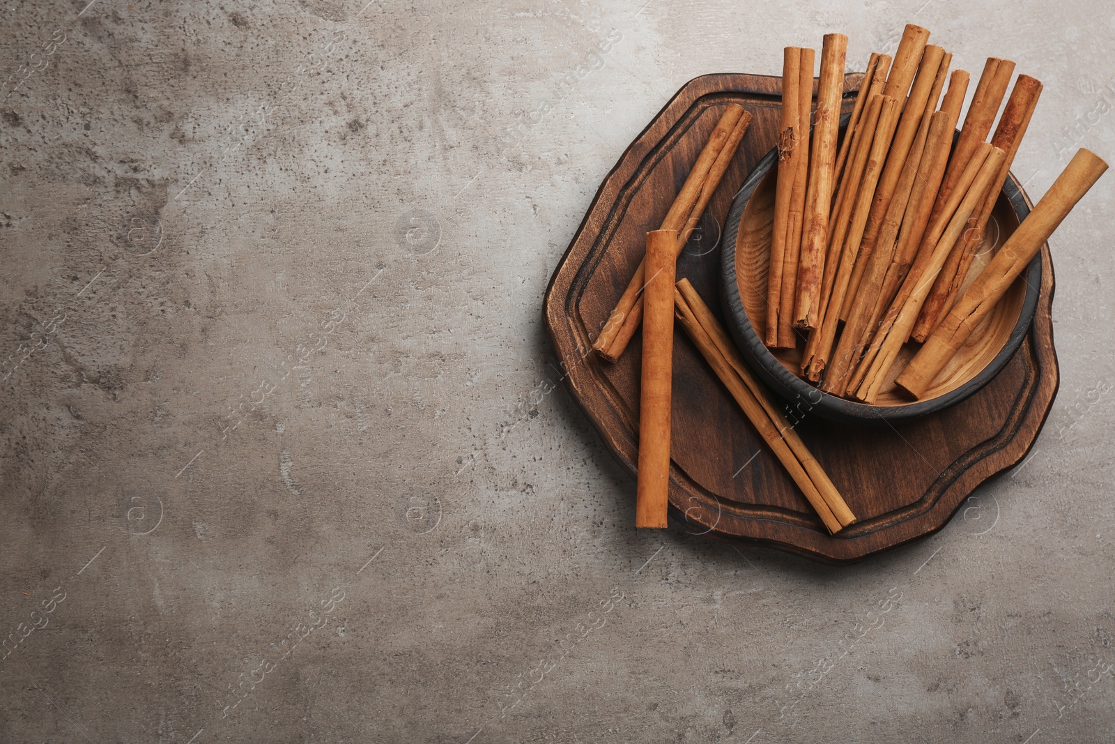 Photo of Aromatic cinnamon sticks on grey stone table, flat lay. Space for text