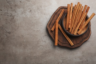 Photo of Aromatic cinnamon sticks on grey stone table, flat lay. Space for text