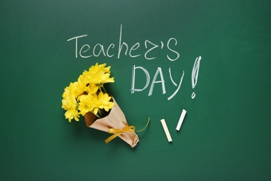 Photo of Flat lay composition with flowers and inscription TEACHER'S DAY on green chalkboard