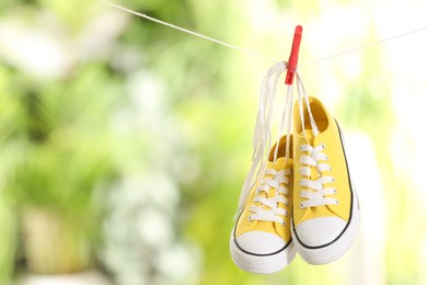 Stylish sneakers drying on washing line against blurred background, space for text