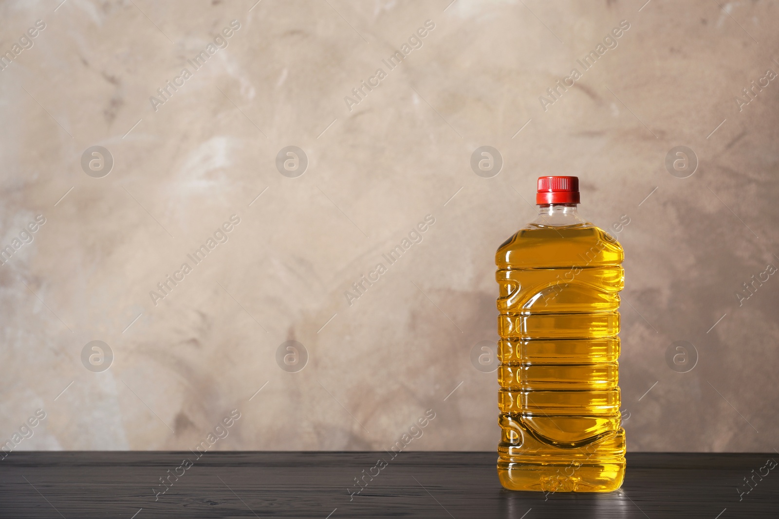 Photo of Bottle of oil on table against color background. Space for text