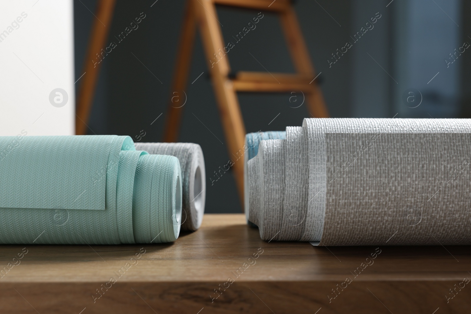 Photo of Different wallpaper rolls on wooden table indoors