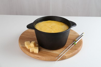 Photo of Fondue with tasty melted cheese and forks on white table