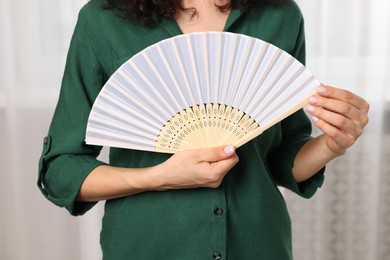 Woman with hand fan indoors, closeup view