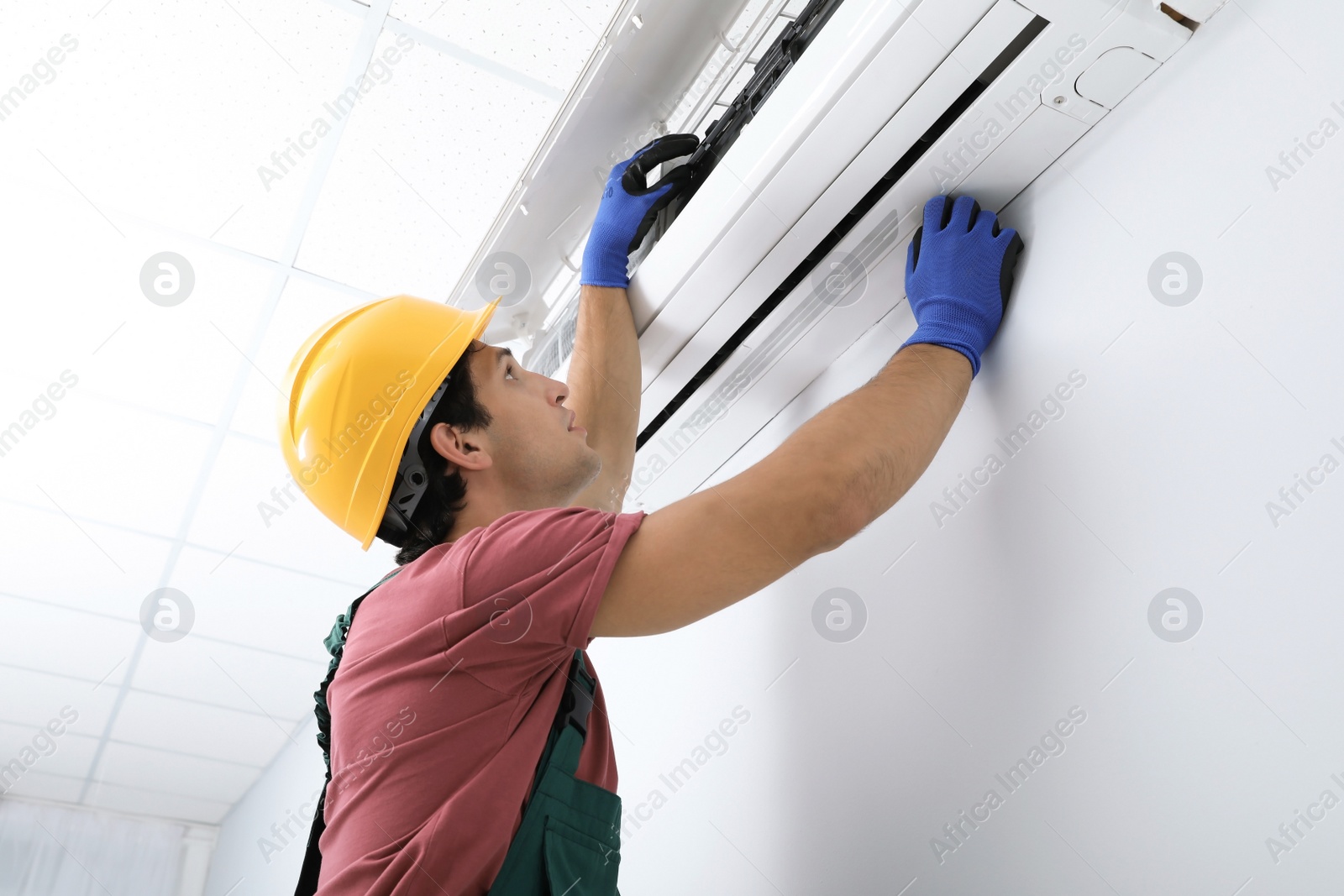 Photo of Male technician checking air conditioner indoors