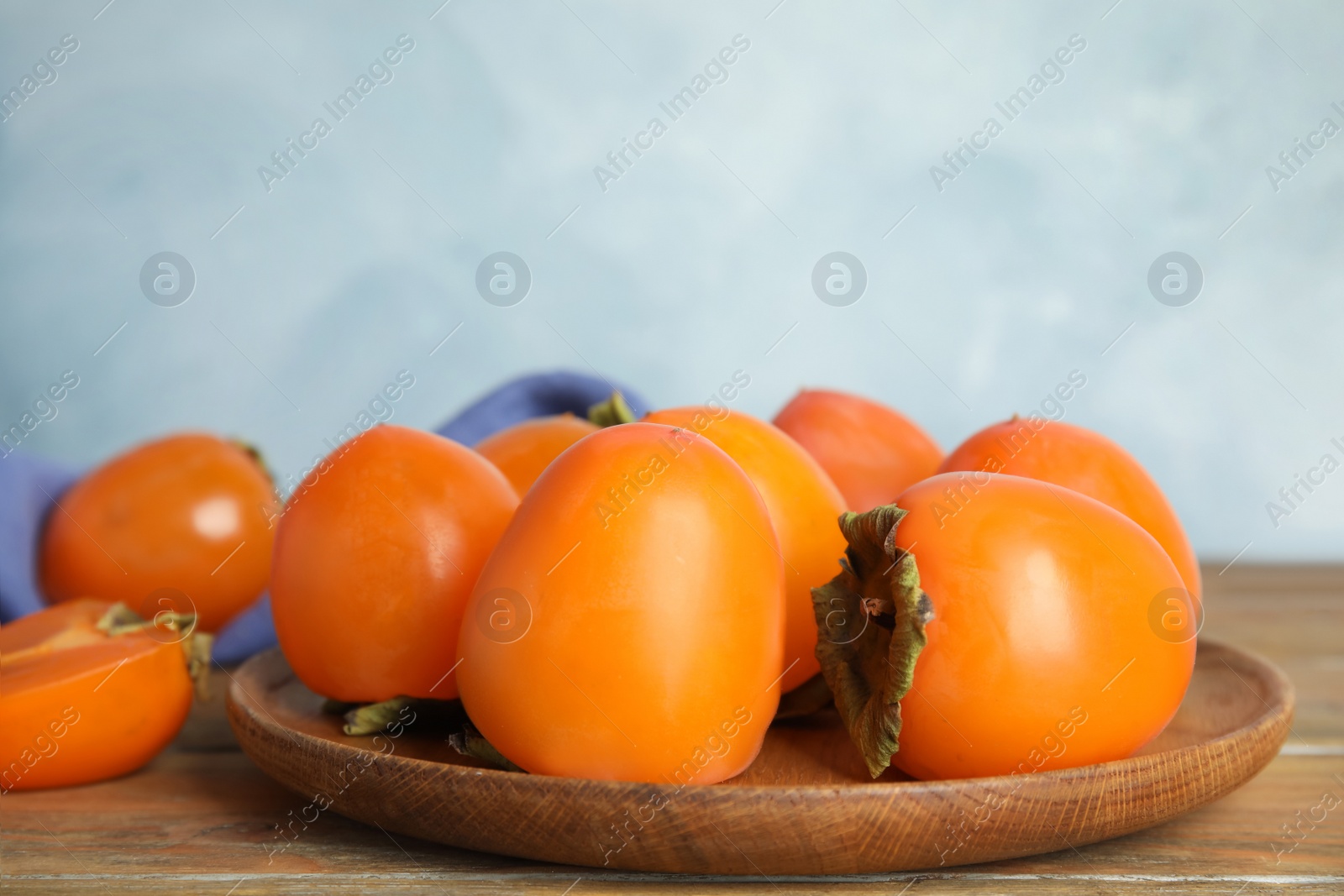 Photo of Tasty ripe persimmons on wooden table, closeup