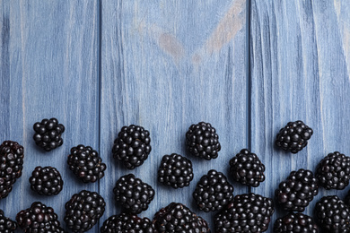 Fresh ripe blackberries on blue wooden table, flat lay. Space for text