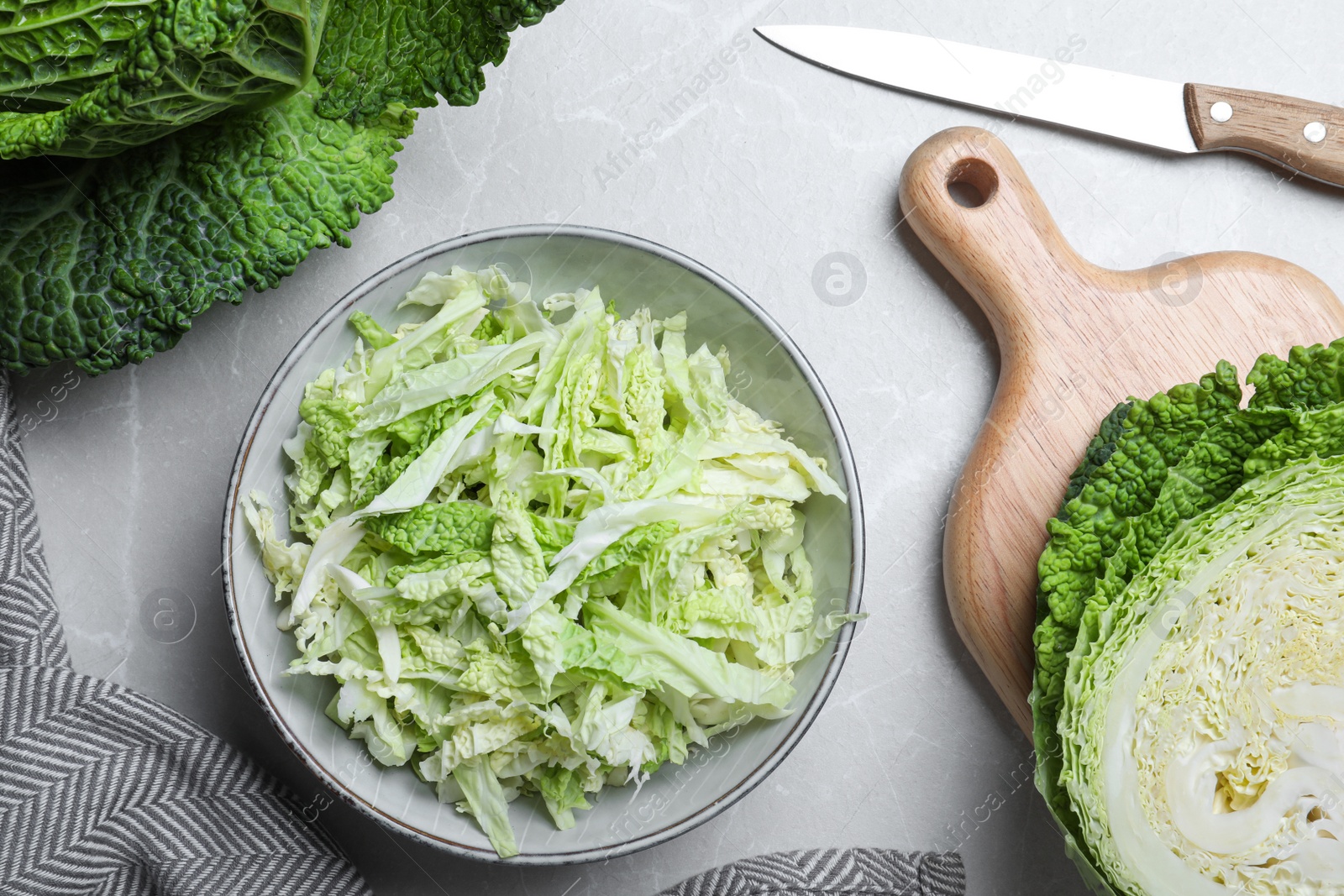 Photo of Cut fresh savoy cabbage on light marble table, flat lay