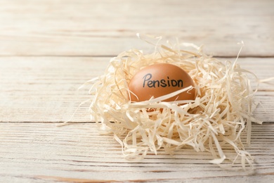 Egg with word PENSION in nest on wooden background. Space for text