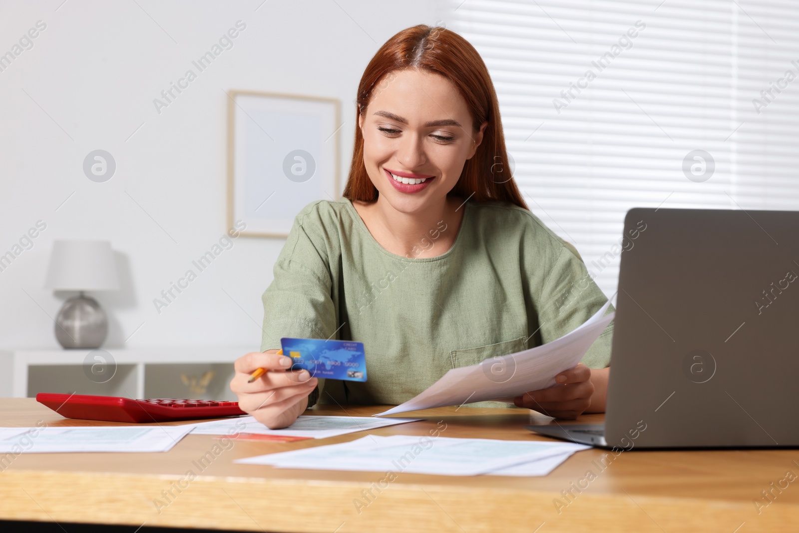 Photo of Woman with credit card using laptop for paying taxes online at home