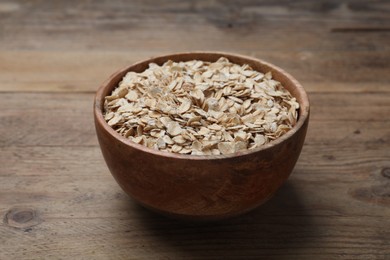 Photo of Bowl of oatmeal on wooden table, closeup