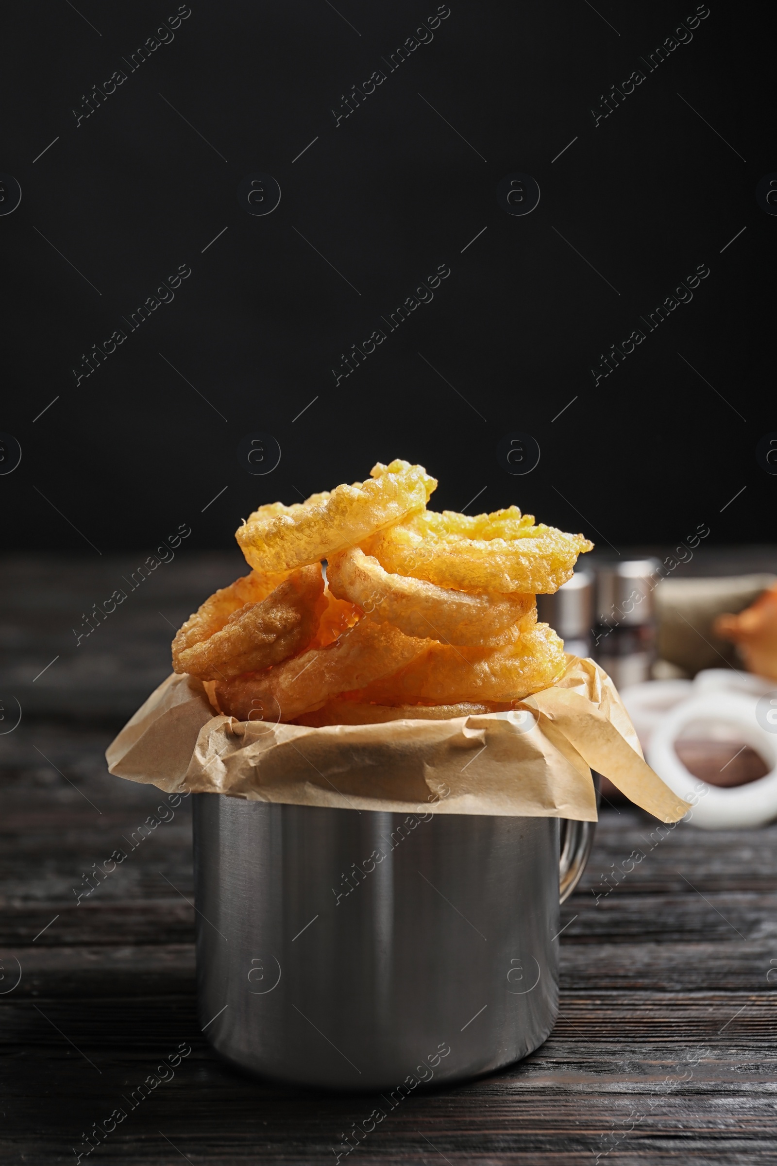 Photo of Dishware with homemade crunchy fried onion rings on wooden table. Space for text