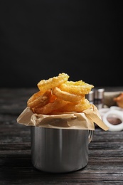 Dishware with homemade crunchy fried onion rings on wooden table. Space for text