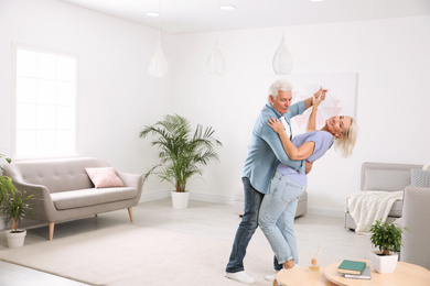 Happy mature couple dancing together in living room