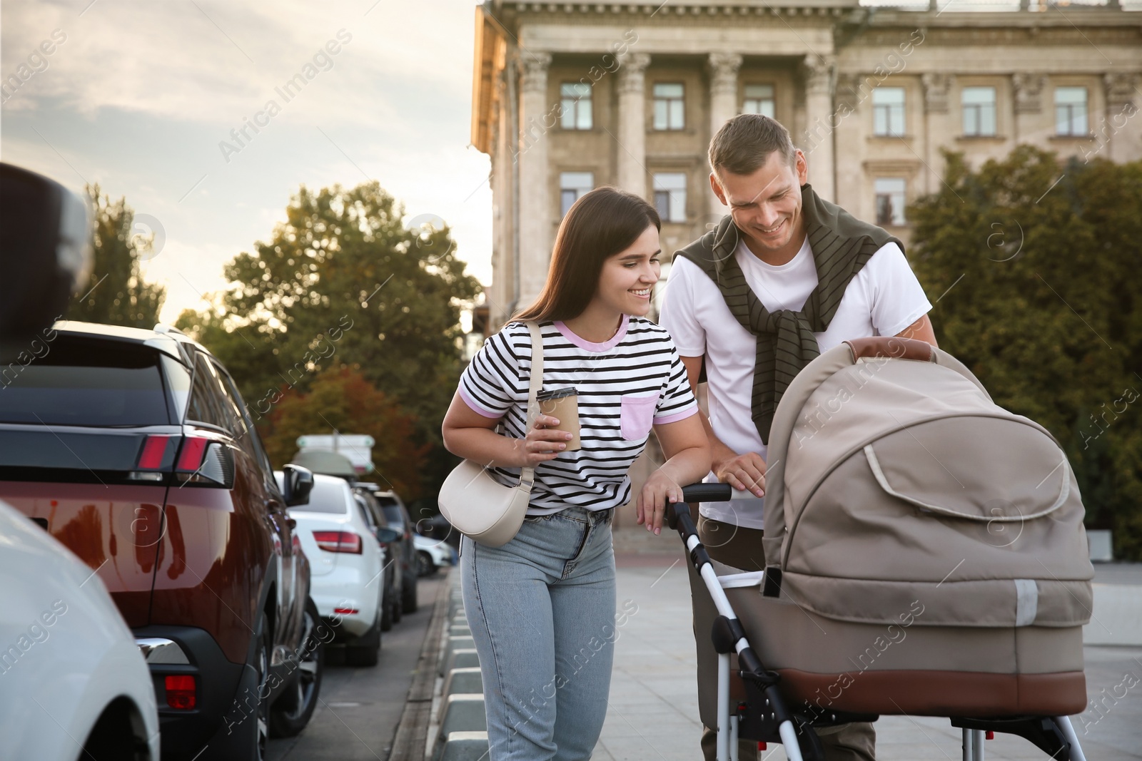 Photo of Happy parents walking with their baby in stroller outdoors