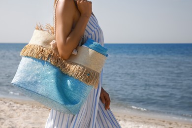 Photo of Woman with beach bag near sea on sunny day, closeup. Space for text