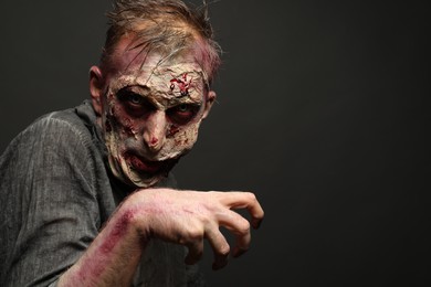 Photo of Scary zombie on dark background, space for text. Halloween monster