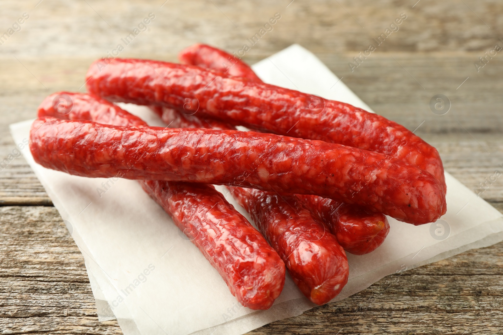 Photo of Thin dry smoked sausages on old wooden table, closeup