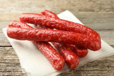 Thin dry smoked sausages on old wooden table, closeup