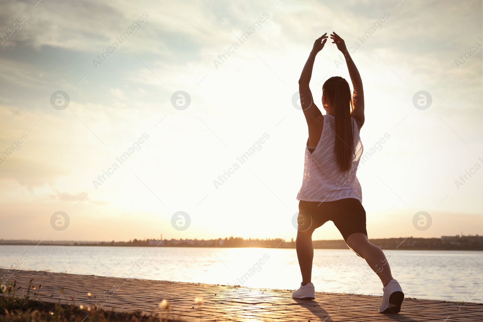 Photo of Young woman doing exercise near river in morning. Space for text