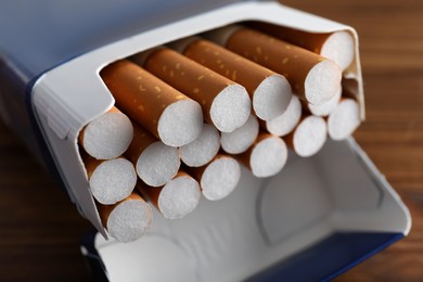 Photo of Pack of cigarettes on wooden table, closeup