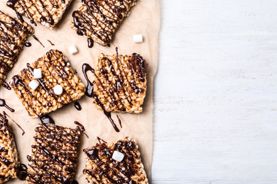 Photo of Delicious rice crispy treats on white wooden table, flat lay. Space for text