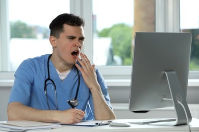 Photo of Exhausted doctor yawning at workplace in hospital