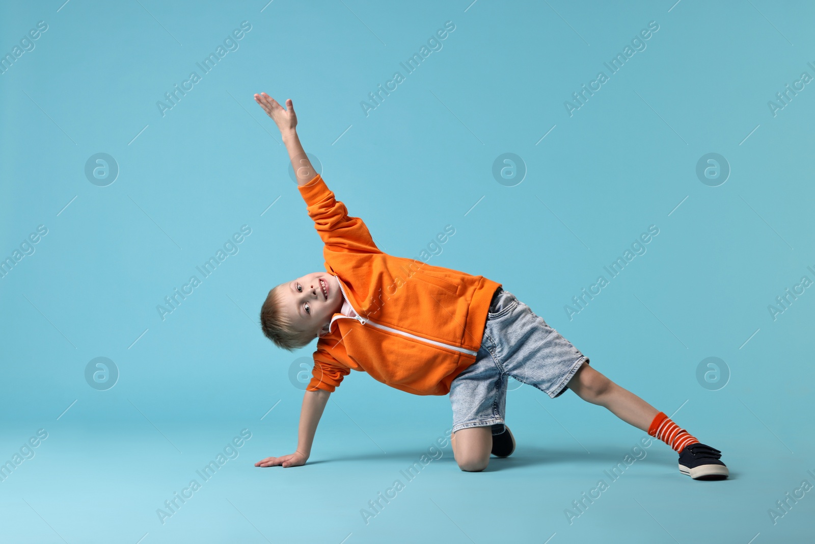 Photo of Happy little boy dancing on light blue background