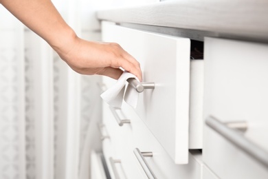 Photo of Woman using tissue paper to open drawer, closeup