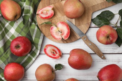 Tasty apples with red pulp and leaves on white wooden table, flat lay