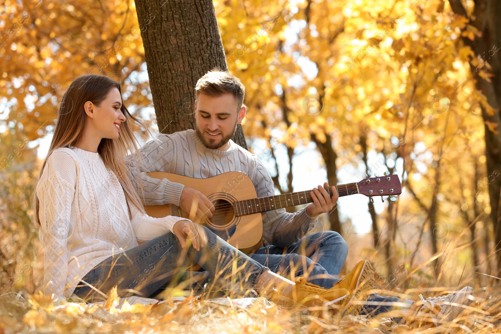 Photo of Young couple with guitar in autumn park