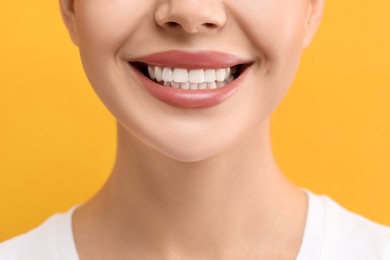 Woman with clean teeth smiling on yellow background, closeup