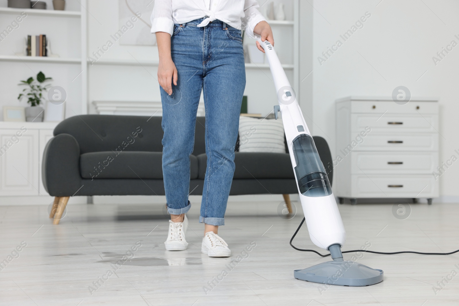 Photo of Woman cleaning floor with steam mop at home, closeup