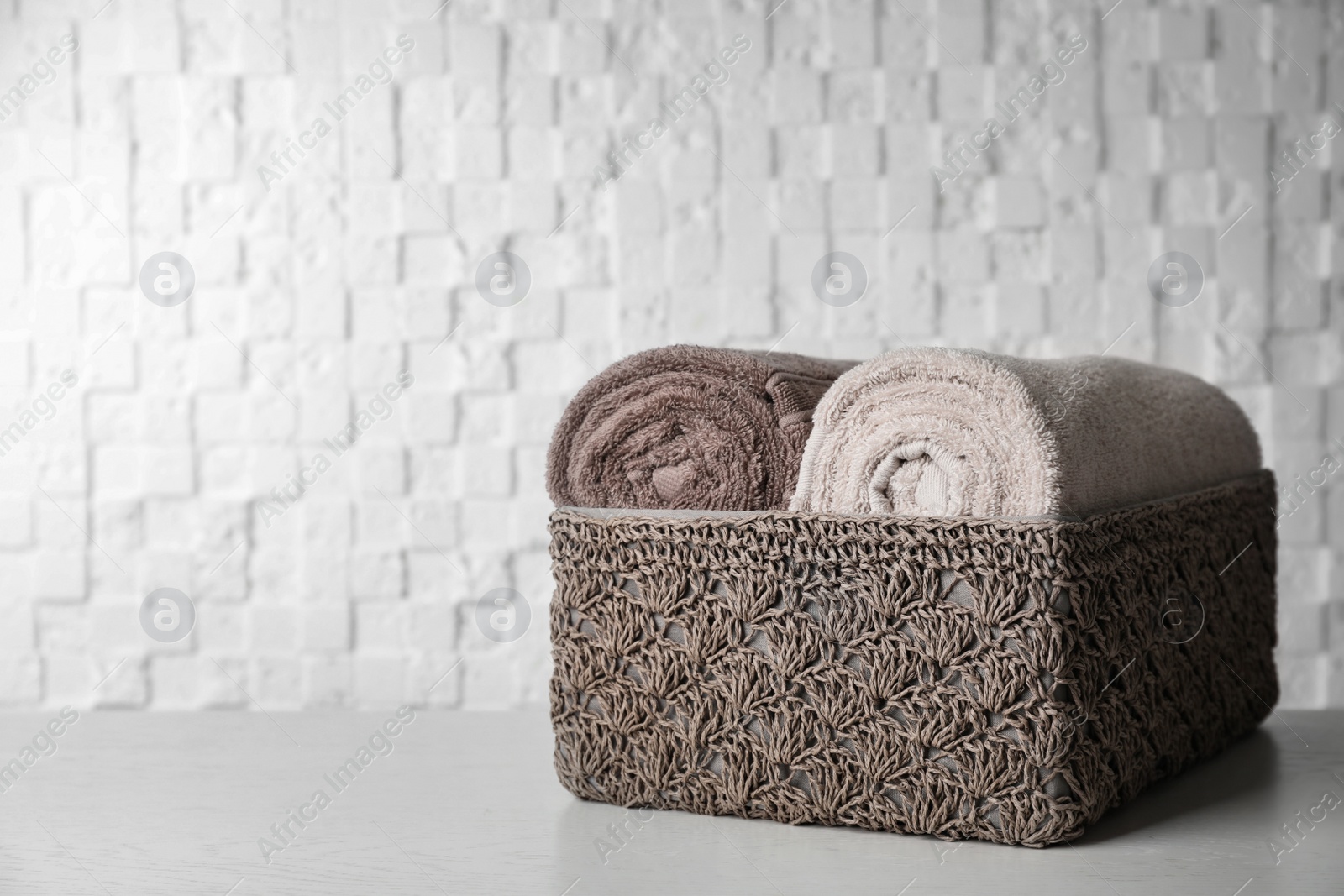 Photo of Basket with soft bath towels on table. Space for text