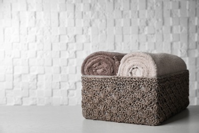 Basket with soft bath towels on table. Space for text