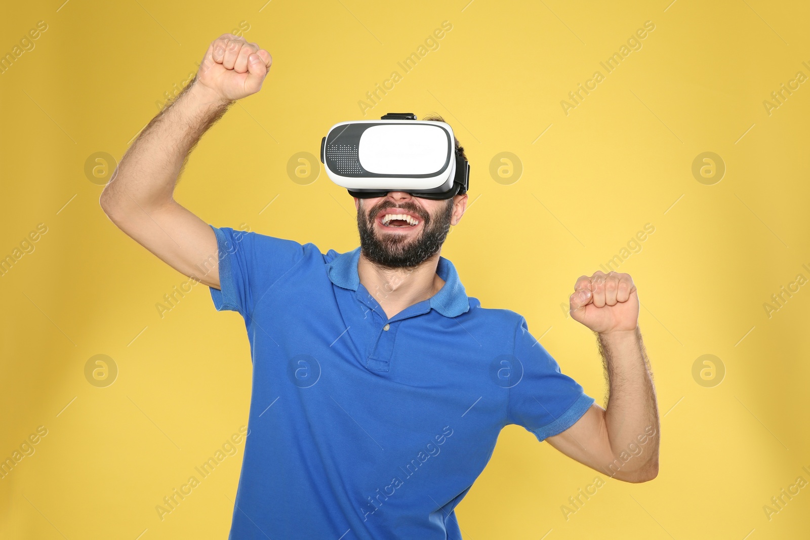 Photo of Emotional young man playing video games with virtual reality headset on color background